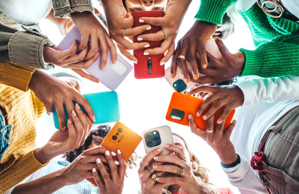 Photo of several young adults in a circle, all looking down at their phones.